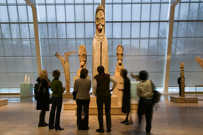 Group in gallery looking at wooden Oceanic sculptures